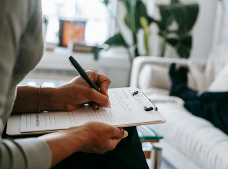 Person writing on paper with a pen, depicting the organization of caregiving tasks.